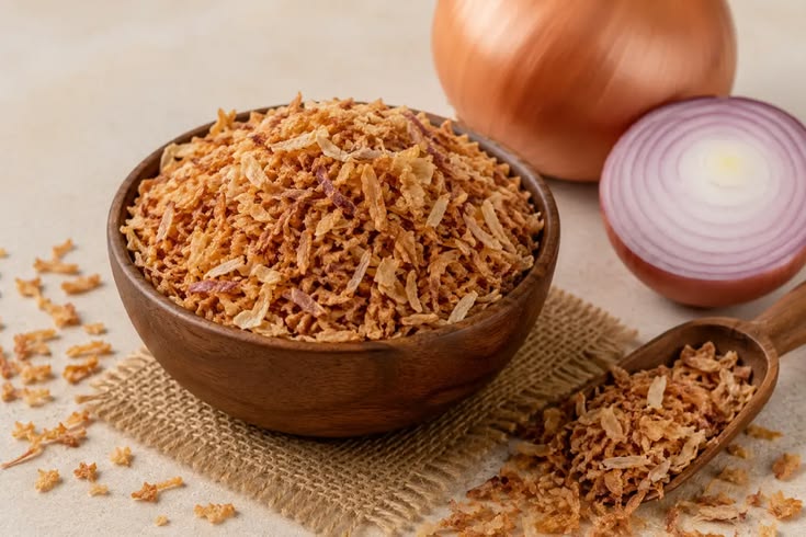Prosesnya cukup sederhana, tetapi beberapa detail menentukan tekstur akhir. Bawang yang terlalu tebal sulit kering merata, sedangkan irisan terlalu tipis mudah berubah warna sebelum bagian dalamnya matang. Karena itu, siapkan alat, wadah peniris, dan tempat penyimpanan sebelum mulai menggoreng agar setiap tahap berjalan lancar. Cara Membuat Bawang Goreng Renyah 1. Pilih Bawang dengan Kondisi Baik Gunakan bawang merah yang masih segar, padat, tidak bertunas, dan bebas dari bagian busuk. Bawang dengan kadar air serta ukuran yang relatif seragam membantu irisan matang lebih merata saat digoreng. Kupas kulitnya, lalu buang bagian yang rusak sebelum mencuci bawang. Setelah mencuci, tiriskan dan keringkan permukaannya agar air tidak memicu percikan minyak ketika proses penggorengan dimulai. Langkah ini juga membantu minyak tetap stabil dan mengurangi risiko bawang saling menempel. 2. Iris dengan Ketebalan Seragam Iris bawang secara tipis dan konsisten supaya setiap potongan matang dalam waktu yang hampir sama. Pisau tajam dapat membantu pekerjaan skala kecil, sedangkan usaha dengan produksi lebih banyak bisa mempertimbangkan mesin perajang bawang dari Rumah Mesin agar proses pengirisan lebih cepat dan seragam. Jangan menumpuk irisan terlalu lama dalam keadaan basah karena kelembapan dapat membuat hasil gorengan kurang garing. Sebarkan irisan di atas wadah bersih dan biarkan permukaannya mengering sebelum masuk ke minyak. Jika menyiapkan banyak bawang, kerjakan secara bertahap agar irisan yang menunggu tidak menumpuk terlalu lama. 3. Gunakan Bumbu Secukupnya Sebagian orang menambahkan sedikit garam untuk memperkuat rasa bawang goreng. Jika memakai garam, campurkan tipis dan merata, lalu segera goreng agar bumbu tidak menarik terlalu banyak air dari irisan bawang. Pelaku usaha makanan juga bisa membuat satu uji coba tanpa tambahan bumbu untuk mengetahui rasa alami bawang. Hindari menambahkan banyak tepung jika ingin menghasilkan bawang goreng dengan tekstur ringan dan rasa bawang yang tetap menonjol. 4. Atur Suhu dan Jumlah Minyak Panaskan minyak dengan api sedang dan pastikan minyak cukup untuk membuat irisan terendam atau bergerak leluasa. Masukkan bawang dalam jumlah kecil agar suhu minyak tidak turun drastis dan irisan tidak saling menempel. Aduk perlahan selama menggoreng supaya panas menjangkau seluruh bagian. Saat bawang mulai berwarna kuning keemasan, segera angkat karena sisa panas masih dapat membuat warnanya semakin gelap setelah keluar dari penggorengan. Hindari meninggalkan wajan tanpa pengawasan karena perubahan warna dapat berlangsung cepat pada tahap akhir. 5. Tiriskan dan Dinginkan dengan Benar Angkat bawang sebelum warnanya menjadi cokelat tua, kemudian tiriskan menggunakan saringan atau kertas penyerap minyak khusus makanan. Sebarkan bawang di atas wadah lebar agar uap panas cepat keluar dan bagian bawahnya tidak menahan kelembapan. Jangan langsung memasukkan bawang yang masih panas ke dalam stoples. Tunggu sampai suhunya turun dan teksturnya kering, sebab uap yang terperangkap dapat membuat bawang cepat melempem. Pastikan wadah penyimpanan tidak menyimpan sisa air dari proses pencucian atau pemakaian sebelumnya. 6. Simpan dalam Wadah Kedap Udara Masukkan bawang goreng yang sudah dingin ke wadah kering dan kedap udara, lalu letakkan di tempat sejuk serta jauh dari sinar matahari. Gunakan sendok yang bersih dan kering setiap kali mengambilnya agar kelembapan tidak masuk ke dalam wadah. Untuk produksi rutin, buat catatan tanggal penggorengan dan jumlah hasil agar stok lama bisa digunakan lebih dulu. Informasi mengenai peralatan pengolahan pangan juga dapat ditemukan melalui situs Rumah Mesin sebagai referensi saat usaha membutuhkan proses kerja yang lebih efisien. Kesimpulan Cara membuat bawang goreng renyah bergantung pada kualitas bawang, ketebalan irisan, pengaturan suhu minyak, dan proses penirisan. Kerjakan setiap tahap dengan rapi agar bawang matang merata dan tidak menyerap minyak berlebihan. Setelah dingin, simpan hasil gorengan dalam wadah kedap udara untuk menjaga kerenyahannya. Jika membuat dalam jumlah besar, pertimbangkan alat perajang yang sesuai kapasitas supaya ukuran irisan lebih konsisten dan waktu persiapan lebih efisien.